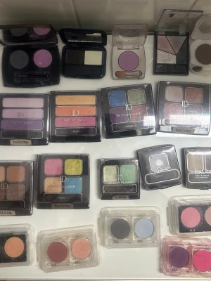 Flera blandade ögonskuggspaletter - Säljer ett stort gäng blandade ögonskuggspaletter från IsaDora, Helena Rubensteini olika färger som lila, blå, grön, rosa, orange, brun och grå. Paletterna innehåller både matta och skimrande nyanser, perfekta för att skapa kreativa och färgstarka ögonmakeuper. Kommer i fyrkantiga och runda förpackningar