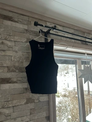 Svart croppad linne - Snygg svart croppad linne från Pieces. Toppen är ärmlös med rund halsringning och har en enkel, stilren design som passar till många olika looks. Perfekt att matcha med höga jeans eller kjol.