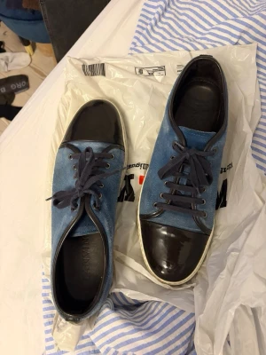 Lanvin sneakers - Uk 11 i storlek. Snygga blå lanvin med svart tå i glansigt material. Skorna har blå snörning och vit sula och material i mocka. Perfekta för dig som gillar en stilren men unik look. Prisförändring och frågor uppskattas. 