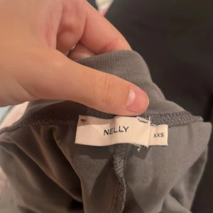 Gråa yogapants från Nelly XXS - Snygga gråa yogapants från Nelly i storlek XXS med lågmidja midja och ett skönt, mjukt material. Byxorna har en loose och wide passform som ger en avslappnad vibe. Perfekta att styla med crop tops eller hoodies för en chill look. Dom är för långa och jag är 158 cm lång. 