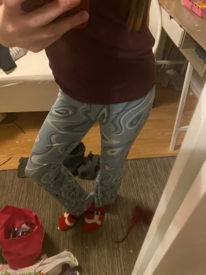 Gröna psykedeliska bootcut byxor - Säljer ett par gröna bootcut byxor med psykedeliskt mönster i olika gröna toner. De har medel midja och är gjorda i ett mjukt, stretchigt syntetmaterial som sitter tight upptill och släpper vid benen. Perfekt för dig som gillar coola mönster.