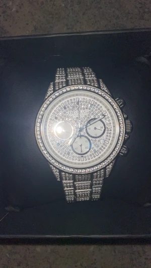 Dissing silverfärgad klocka med stenar - Säljer en riktigt blingad klocka från Dissing i silverfärgat rostfritt stål. Urtavlan och länken är täckta med glittrande stenar, och klockan har kronograf-funktion samt datumvisning. Vattentät till 10 ATM och japanskt urverk. Extra länkbitar medföljer. Kan skicka en video på klockan om det skulle önskas. Kvitto finns! Tveka inte att höra av er vid några frågor eller funderingar🤗