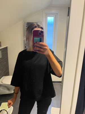 Svart stickad tröja - En svart stickad tröja med loose passform och trekvartsärm. Enkel och stilren design som funkar till många olika looks. Mjuk och skön, perfekt för dig som gillar oversized vibe och vill ha något bekvämt och snyggt.