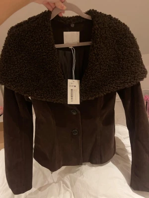 NA-KD jacka i mocka med fårskinnskrage  - Säljer denna jacka från Lovisa Worges kollektion. Jackan är helt ny och oanvänd med prislapp. Fårskinnskragen går att ta bort för att få en annan look. Nypris på jackan är 1300kr. Storleken är 34 och passar på mig som brukar ha XS/S💕 stl 34 är en väldigt populär storlek och är därför helt slutsåld.