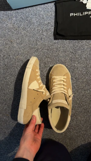 Beige Philippe Model sneakers mocka - Snygga beige sneakers från Philippe Model med rund tå och platt sula. Skorna är tillverkade i mocka och skinn, har ljusa snören och diskreta logodetaljer på plös och häl. Perfekt för dig som gillar stilrena och neutrala färger. Använda 2 gånger så helt nyskick! Hör av er vid frågor!😊