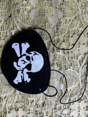 Svart ögonlapp med dödskalle - Cool svart ögonlapp med vit dödskalle-tryck, perfekt för piratlooken. Elastiskt band för enkel användning. Materialet är mjukt och bekvämt mot huden. Passar dig som vill sticka ut på temafesten eller cosplay.