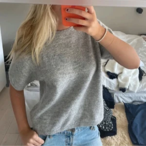 Grå stickad tröja från Gina Tricot - Supermysig grå stickad tröja från Gina Tricot med tre kvarts ärm. Tröjan har en loose passform och är tillverkad i mjuk ullmix som känns skön mot huden. Perfekt att styla med jeans eller kjol för en chill look.