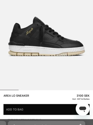 Svarta Area Lo sneakers från Axel Arigato - Stilrena Area Lo sneakers från Axel Arigato i svart skinn med vit och beige sula. Snygg guldfärgad Arigato-logga på sidan, perforerade detaljer och klassisk snörning. Perfekta för dig som gillar en clean och modern look.  Pris går defenerivt att disskutera