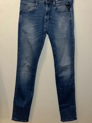 Replay Anbass jeans blå slim fit - Snygga blå Replay Anbass jeans med slim fit och klassisk femficksdesign. Jeansen har ljus tvätt, svarta detaljer och tydliga sömmar på bakfickorna. Materialet är mjukt jeans och passformen är smal med normal midja. Perfekt för dig som gillar stilrena och moderna jeans. Riktigt schyssta!