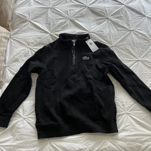 Svart half zip tröja från Lacoste - Svart långärmad tröja från Lacoste. Storlek M men sitter som S