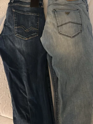 Replay Anbass Hyperflex jeans blå och armani jeans ljusblå - Säljer ett par Replay Anbass Hyperflex jeans i storlek 34. De är blå med snygga slitningar och klassisk femficksdesign. Jeansen har stretchigt material för extra komfort och cool detalj med Replay-logga på bakfickan. Perfekt för dig som gillar stilrena jeans med lite edge. Armani jeansen är supersköna storlek 34 cool ljus tvätt.