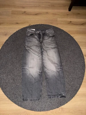 Grå baggy jeans från H&M loose fit - Säljer ett par grå jeans från H&M med baggy loose fit. Jeansen har en tvättad look med ljusare partier framtill och baktill, klassiska fem fickor och raka ben. Perfekt för dig som gillar avslappnad stil och bredare passform. 