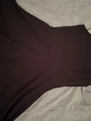 Svart långklänning med ärmlös design - Säljer en stilren svart långklänning med ärmlös design och rund hals. Klänningen har en enkel, elegant siluett och är tillverkad i ett mjukt material som faller snyggt. Storlek: 158-164 ålder: 12-14