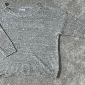 Grå stickad tröja med rund hals - Mysig grå stickad tröja med rund hals och 3/4 ärmar. Tröjan har en enkel design med ribbade muddar vid ärmslut och nederkant. Perfekt för kyliga dagar och enkel att matcha med olika outfits.❤️