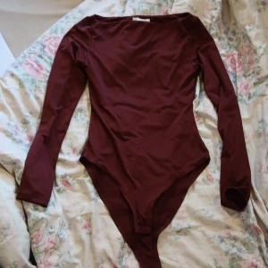Vinröd långärmad body från H&M - Säljer en vinröd långärmad body från H&M i storlek XS. Den har en enkel, stilren design med rundad hals och är tillverkad i ett mjukt stretchigt material. Perfekt att styla med jeans eller kjol för en snygg look.
