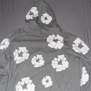 Grå hoodie med blommor från Denim Tears - Säljer min hoddie på grund av att den är för liten för mig. Haft den ett tag men inte använt den så mycket. Passar perfekt till hösten och vintern 