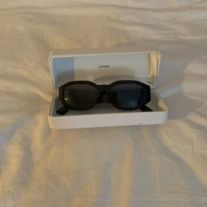 Svarta solglasögon  - Snygga svarta solglasögon med markerad, kantig båge och mörka glas. Perfekta för dig som vill ha en stilren och modern look med lite edge.