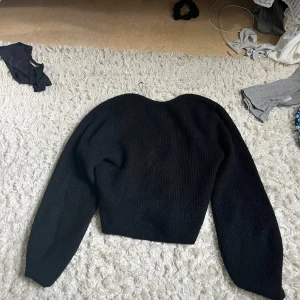 Svart croppad stickad tröja - Säljer en svart croppad stickad tröja med lång ärm och fyrkantig ringning. Tröjan har en enkel och stilren design som passar perfekt till jeans eller kjol. Mjuk och skön att bära, perfekt för kyligare dagar.