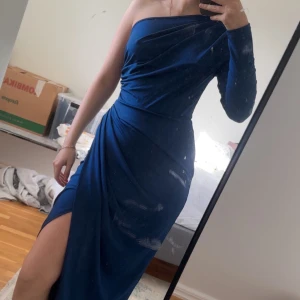 Marinblå långklänning oneshoulder - Säljer en marinblå långklänning med oneshoulder och lång ärm. Bra inför bal eller bröllop:), materialet är stretchig.