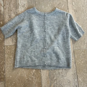 Grå kortärmad kofta med pärlknappar - Superfin ljusgrå kofta med korta ärmar och pärlknappar framtill. 