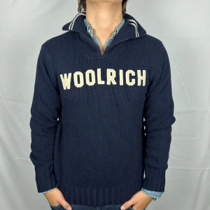 Woolrich Halfzip Cardigan - Stickad Halfzip tröja från Woolrich. Storlek: L enligt tagg men passar även M - Skicket på tröjan är väldigt bra utan defekter - Vårat pris: 849kr - Nypris: 3000kr - Modellen är 185cm och väger 80kg. Hör av dig vid frågor eller funderingar!
