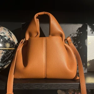 Brun handväska från Polène i skinn - Säljer en snygg brun handväska från Polène i mjukt, strukturerat skinn. Väskan är i färgen Camel i storlek mini. Aldrig använd. Säljer då färgen inte passade mig☺️dustbag följs med