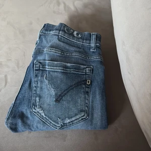 Dondup George Skinny Fit jeans blå - Snygga blå jeans från Dondup, modell George Skinny Fit. Jeansen har slitna detaljer och en klassisk femficksdesign. Tillverkade i denim med en smal passform som sitter tajt längs benen. 