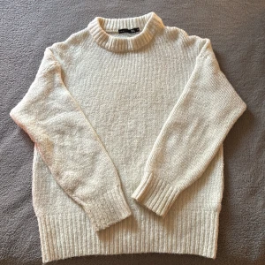 Vit stickad tröja från 157 - Mysig vit stickad tröja från 157 med rund halsringning och ribbing vid ärmslut och nederkant. Perfekt för lager-på-lager under kyliga dagar. Enkel och stilren design som passar till allt. Säljer pga fel storlek. Pris kan diskuteras. Skriv för fler bilder. 
