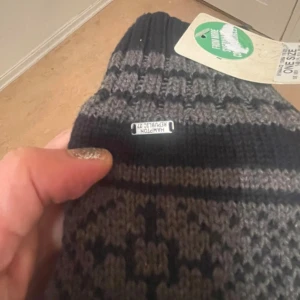 Stickade vantar Hampton Republic - Mörkgrå och svarta stickade vantar från Hampton Republic med klassiskt nordiskt mönster. Utsidan är i mjuk stickad ullblandning och insidan fodrad med varm fleece. Perfekta för kalla vinterdagar och snygga till alla ytterkläder.