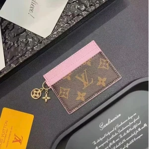 Card Holder  - Stylish card holder featuring a timeless brown canvas design with pink details. The gold-tone charms and practical compartments create the perfect everyday accessory for your cards. Delivered in its box and in excellent condition, this card holder is ideal for anyone looking for a luxury accent with convenience. Sold as pictured