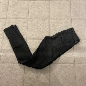 Svarta jeans från Replay - Snygga svarta jeans från Replay med smal passform och klassisk femficksdesign. Jeansen har en diskret tvättad look och är tillverkade i stretchigt jeansmaterial för extra komfort. Perfekta för dig som gillar en tight och stilren stil.