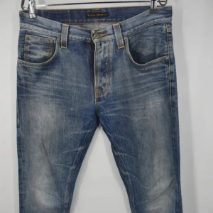 Nudie Jeans  - Ljusblå jeans från Nudie Jeans, modell Big Bengt. Jeansen har klassisk femficksdesign, orange kontrastsömmar och snyggt slitna detaljer framtill och baktill. Tillverkade i 100% bomull för en skön känsla och avslappnad look. Om ni har några frågor är det bara att höra av er. Kom gärna med prisförslag// Loke
