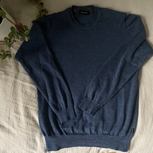 Blå tröja i merinoull från Sand Copenhagen - Klassisk mörkblå rundhalsad tröja i 100% merinoull från Sand Copenhagen. Tunnstickad modell med ribbade muddar vid ärmslut och nederkant.              📏Storlek: M ✨ Skick: Lite använd men i mycket bra skick, inga fläckar eller hål. 🧵 Material: Merinoull – mjuk, skön och värmande.       ✅ Pris kan diskuteras