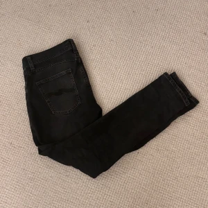 Mörkgråa nudies 29/30 - Säljer ett par mörkgråa jeans från Nudie Jeans i storlek 29/30. Klassisk femficksmodell med Nudie-söm på bakfickorna. Modellen är lean Dean. Ställ gärna frågor!
