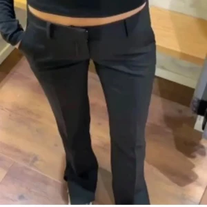 Svarta bootcut kostymbyxor - Snygga svarta kostymbyxor med bootcut passform och låg midja. Byxorna har klassiska fickor fram och bak, hällor för bälte och är tillverkade i ett slätt tyg som ger en dressad look. Perfekta för dig som gillar stilrena och trendiga byxor.