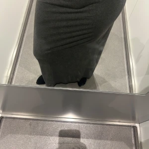 Mörkgrå långkjol i mjukt material - Säljer en stilren mörkgrå långkjol med rak passform. Kjolen är enkel och tidlös, perfekt för dig som gillar minimalistisk stil. Materialet känns mjukt och följsamt mot kroppen. Passar dig som vill ha en klassisk och bekväm kjol till garderoben.