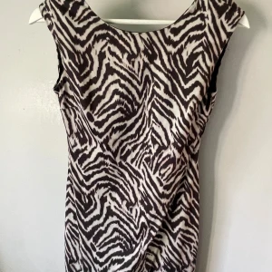 Zebramönstrad klänning från H&M XS - Snygg zebramönstrad klänning från H&M i svart och vitt. Modellen är ärmlös med rundad halsringning fram och djupare rygg. Klänningen är figurnära och kort, perfekt för dig som vill sticka ut med ett coolt mönster.