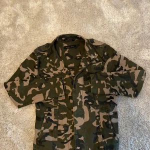 Zara Man overshirt  - Säljer en snygg camouflage jacka från Zara Man med klassisk militärstil. Jackan har flera fickor framtill, axelklaffar och stängs med både dragkedja och knappar. Passar som XS. Pris diskuterbart.