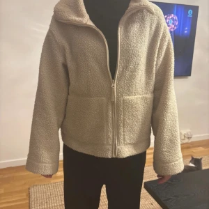Beige teddyjacka med dragkedja M - Mysig beige teddyjacka i storlek M med hel dragkedja framtill och två stora fickor. Den är i bra skick och finns inte att köpa längre 