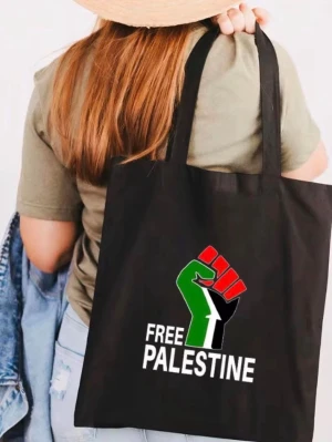 Palestina  shoppingväska med Free Palestine-tryck - Säljer en svart shoppingväska med ett färgstarkt tryck som visar en knuten näve i rött, grönt, svart och vitt samt texten 'Free Palestine'. Tygväska Vita Kvinnor Män Handväska  Produktstorlek: 380,00 x 340,00 x 20,00 MM/14,96 x 13,39 x 0,79 tum  Form: Vanlig tygväska med stor kapacitet  Huvudmaterial: Polyester Bomull .Väskan har långa han