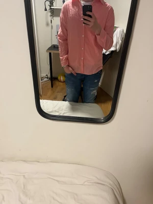 Ljusrosa skjorta med knappar - Säljer en ljusrosa skjorta med klassisk krage och vita knappar framtill. Skjortan har lång ärm och en loose passform som ger en chill vibe. Perfekt för dig som gillar stilrena plagg med enkel design.