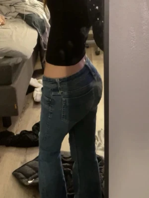 Blå bootcut jeans med låg midja - Storlek S (36) men passa nog xs också. Säljer ett par blå jeans med klassisk bootcut och låg midja. Jeansen har fem fickor, knapp och dragkedja framtill samt snygga sömmar längs benen. Materialet är jeans och färgen är en mörkare blå ton. Perfekt för dig som gillar retrovibbar och avslappnad stil. Lite lite slitna ner till (som de flesta jeans blir) men inget man tänker på. 