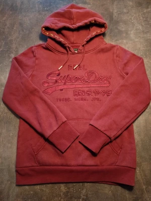 Superdry Hoddie  - Fin röd/vinröd Hoddie i toppskick inga defekter alls. Modellen på bilden är 175cm lång och väger 80kg. Passar liten S