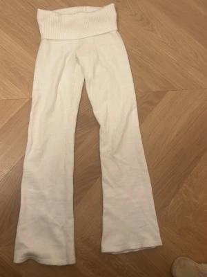 Vita ribbade byxor från Gina Tricot - Säljer ett par vita byxor från Gina Tricot med bred ribbad midja. Byxorna har en rak passform och är gjorda i mjukt material som känns skönt mot huden. Perfekta för en chill och avslappnad stil.