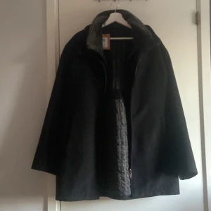 Svart kappa i kashmir och ull - Säljer en svart kappa från Cashmere and Wool, tillverkad i Italien. Jackan har en klassisk rak passform, diskreta fickor och är helsvart med snyggt mönstrat innerfoder. Materialet är en lyxig blandning av kashmir och ull som känns mjuk och varm. Stl 3 vilket motsvarar L. Priset är diskuterbart.