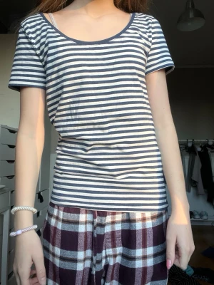 Randig t-shirt med rund hals hm - Säljer en klassisk t-shirt med marinblå och vita horisontella ränder. T-shirten har rundad hals och korta ärmar, perfekt för en chill och enkel stil. Materialet känns mjukt och skönt mot huden, troligtvis bomull. Passar dig som gillar basic och tidlös design.