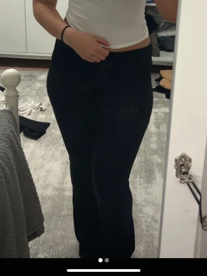 Svarta yogapants - Säljer ett par svarta bootcut byxor med hög midja. De är gjorda i mjukt bomullsmaterial och har en stilren, enkel design utan synliga detaljer. Passformen är normal och byxorna sitter snyggt över höften och låren innan de blir vidare nedtill. Slitna i änden.