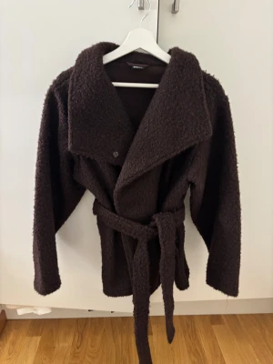 Brun teddyjacka med bälte Gina Tricot - Mysig brun teddyjacka från Gina Tricot i storlek XS. Jackan har bred krage, långa ärmar och ett matchande bälte i midjan för extra stilpoäng. Perfekt för dig som gillar oversized look och vill ha en varm jacka med cool textur.