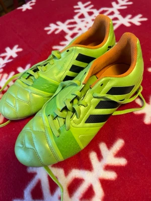 Adidas nitrocharge 3.0 fotbollsskor lime - Säljer ett par Adidas nitrocharge 3.0 fotbollsskor i en riktigt fet limegrön färg med svarta ränder och orange insida. Skorna har snörning och är tillverkade i syntetmaterial, perfekta för dig som vill sticka ut på planen.