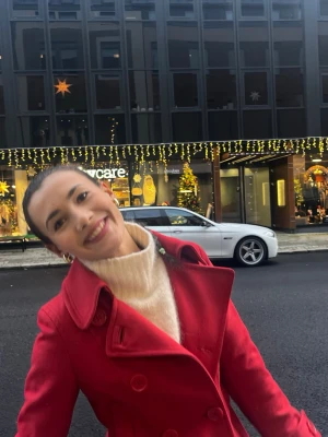 Röd kappa med dubbelknäppning - Säljer en snygg röd kappa med klassisk krage och dubbelknäppning. Jackan har en stilren design och är perfekt för dig som vill sticka ut i vintermörkret. Passar lika bra till jeans som till klänning och håller dig varm under kyliga dagar.